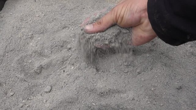 man hand picks up fireplace ash to use at home or in the garden for plants