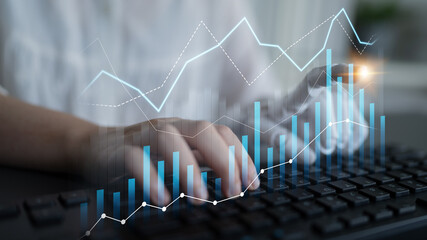 A business professional engages in data analysis with digital graphs overlaid on a keyboard, showcasing a modern workspace environment focused on metrics. Scalp