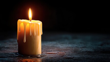 Lit candle with dripping wax on a dark surface.
