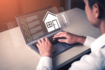 A professional man interacts with a laptop displaying virtual home icons and checklists, showcasing...
