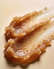 Hyper-realistic studio photography of cosmetic textures, swatch of a dark brown coffee sugar scrub on a beige gradient background