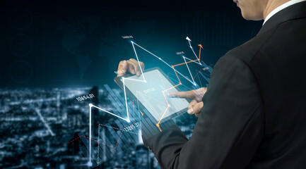 Business professional reviews data trends using a tablet in a high-tech environment. The image showcases digital graphs and analytics, emphasizing modern technology usage. Scalp