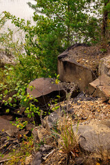 Fototapeta premium Natural rock quarry with columnar basalt formations and textured stone surfaces in forest surroundings.