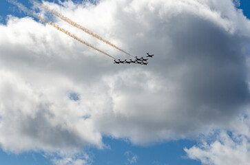 Formation of acrobatic jets flying under dark gray clouds
