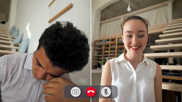 A man sits bored during an online call. A woman in a white shirt shows a cheerful expression. The setting has a staircase in the background. The call seems to lack energy.