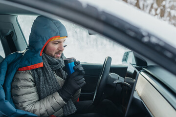 Driver staying warm in electric car during winter © dsheremeta