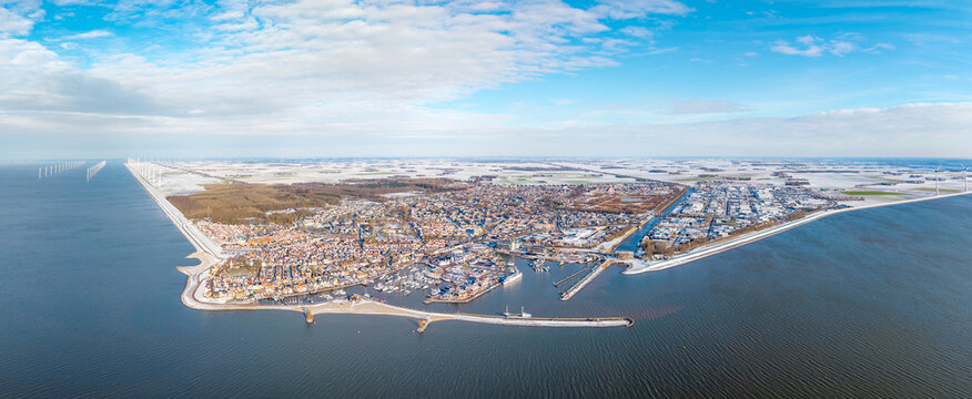 Aerial panorama of Dutch harbor town in winter with offshore wind farm