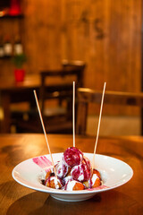 Dessert fritters drizzling berry sauce on wooden table