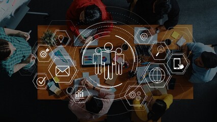 Aerial view of a diverse group engaged in a business meeting with digital interface overlays highlighting collaboration and innovative technology in a modern workspace. Raster