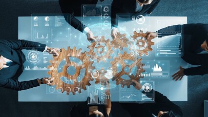A dynamic scene of business professionals engaged in collaboration around a table, using digital tools and wooden gears to represent teamwork, strategy, and innovation. Raster