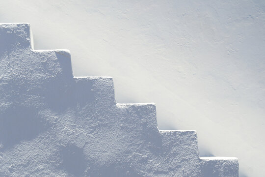 Minimal whitewashed concrete steps on a bright white wall