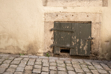 Small wooden cellar door set in old building wall
