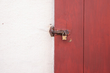 Red wooden door secured with metal padlock
