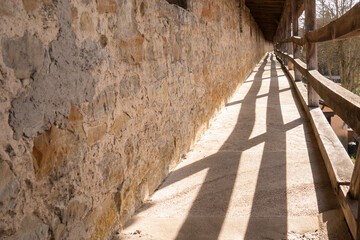 Empty historic covered walkway with stone wall perspective
