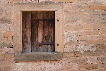 Small wooden window set in historic stone wall
