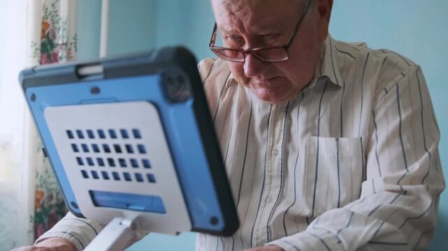 Older Gentleman Examining Device Carefully - Senior White Man Concentrates On His Digital Screen Attentively - An Elderly Caucasian Man Thoughtfully Adjusts His Tablet Within Cozy Reading Nook At