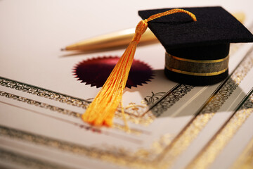 small mortarboard ,pen on a blank  certificate on blue backlground.