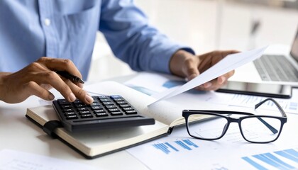 Professional at desk analyzing financial documents with calculator and charts.