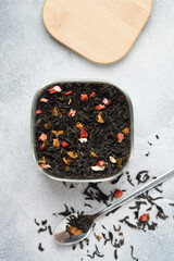 Black leaf tea with fruit additives (strawberry, raspberry, apple, pear, feijoa) in a glass jar  on a gray background. A delicious and healthy drink. Selective focus