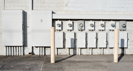 Multiple electrical meters and control boxes located on a wall in a urban area during daylight