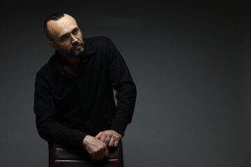 Obraz premium Fashion model. Handsome man with chair on grey background, space for text