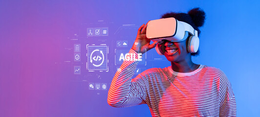 A joyful woman engages with a virtual reality headset, immersed in an agile tech interface against a vibrant blue background, showcasing modern digital experiences. XDMCP