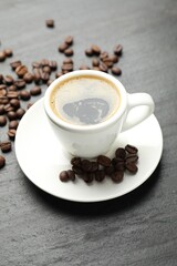 Obraz premium Refreshing coffee in cup and beans on dark textured table