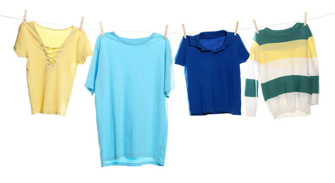 Different clothes drying while hanging on clothesline against white background