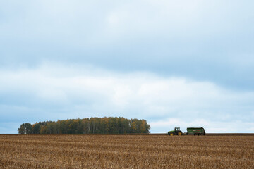 MINSK, BELARUS - NOVEMBER 2019: tractor spreads organic fertilizer on the field on a cloudy day