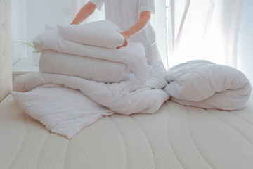 Woman Refreshing Bedding and Arranging Pillows in a Warm Winter Bedroom for Seasonal Stay