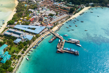 Top view or aerial view of beautiful crystal clear water beach pier port with boats, ferries and...