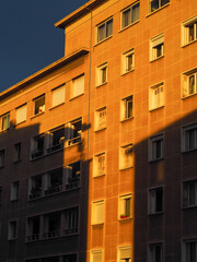 Obraz premium Façade d'immeuble moderne à Marseille sous la lumière dorée du lever de soleil, jeu d'ombres géométriques