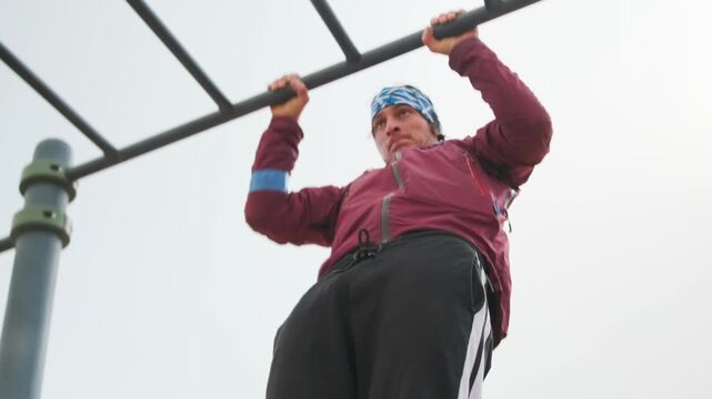 Park Pullup Effort - Someone Doing Pullups At Park Under Cloudy Skies - Individual Exercises On Outdoor Bars With Strong Focus - Person In Park Performing Pullups With Dedication On Outdoor Fitness