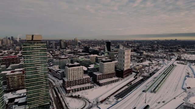 Stunning 4K drone footage of Toronto's iconic skyline at winter sunrise, flying over the Gardiner Expressway bridge amid a pristine snowscape.