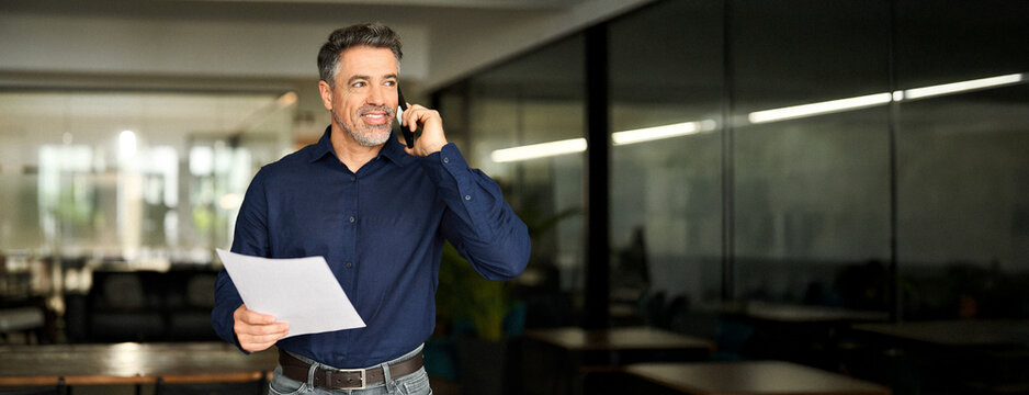 Busy older business man hr manager of middle age making call in office. Mature senior businessman executive, lawyer or entrepreneur holding documents talking on the phone at work consulting client.