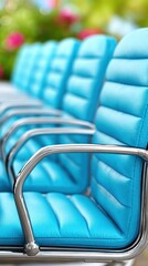 Fototapeta premium A row of blue chairs are lined up in a row. The chairs are all the same color and have a similar design. The chairs are arranged in a way that they are facing the same direction