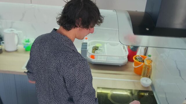 Young man washing, Caucasian guy cleaning dishes, Male individual rinsing breakfast tableware diligently, Young Caucasian male engaged in regular morning kitchen cleanup and dish washing routine