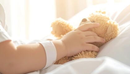 Teddy Bear Comforts Hospitalized Child: A child's hand gently embraces a beloved teddy bear on a hospital bed, exuding a sense of security and innocence. The soft sunlight casts a comforting glow.