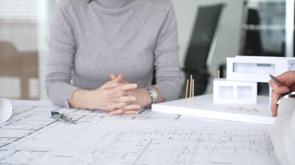 Architects collaborating, examining building blueprints with rulers and pens, developing innovative architectural designs and construction plans around a model house, close up - Powered by Adobe