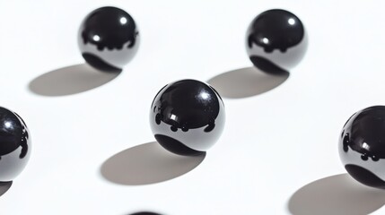 Polished obsidian spheres of different diameters casting shadows on a white background
