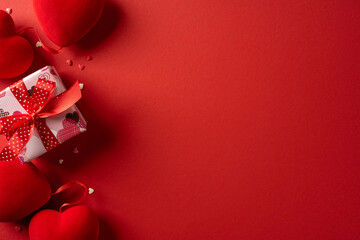A red gift box tied with a red ribbon sits on a deep red backdrop, surrounded by tiny hearts, conveying love and celebration for Valentine’s Day greetings and romance