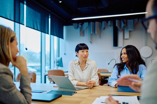Diverse business professionals discussing and collaborating during an informal meeting in a modern open-plan office space - Powered by Adobe