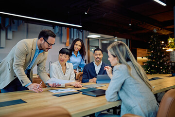 Multi-ethnic business professionals discussing documents and ideas, fostering teamwork and collaboration in a modern office
