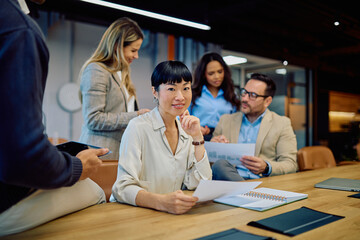 Diverse business team collaborating during a corporate meeting, analyzing data and discussing strategy in a modern office setup