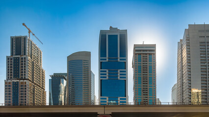 Modern skyscrapers and a construction crane in Dubai city skyline on a sunny day