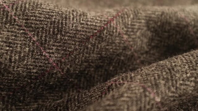 Hands touching soft wool fabric. Dark grey English tweed plaid wool fabric. Appreciating pleasant texture of high quality textile for clothes. Soft and cosy textile. Dark color winter knitted textile.