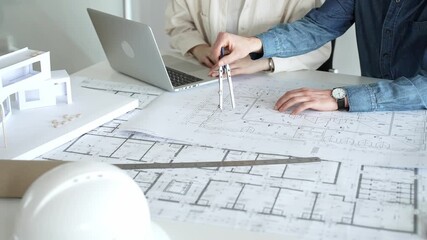 Architects collaborating on architectural blueprints and building plans, designing a new house project with a model, laptop, and safety helmet on a desk in an office - Powered by Adobe