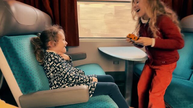 Two Young Girls Playing with Toy Binoculars Inside Passenger Train