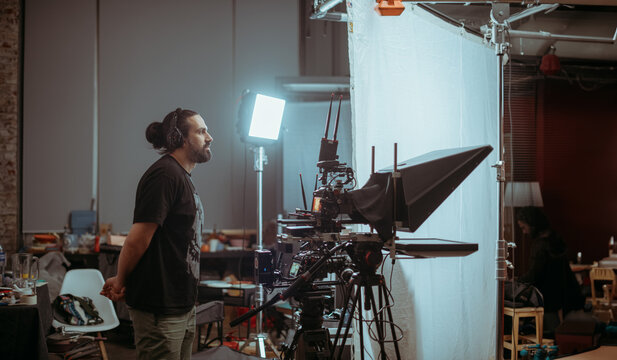 Director of photography with a camera in his hands on the set. Professional videographer at work on filming a movie, commercial or TV series. Filming process indoors, studio