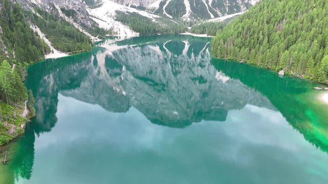Vue a&eacute;rienne cin&eacute;matique du lac de Braies avec les reflets des montagnes des Dolomites et ses barques en bois